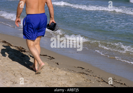 Uomo a camminare a piedi nudi sulla spiaggia Foto Stock