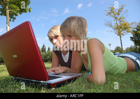 Junge Mädchen mit laptop auf wiese - giovani ragazze giacente in erba lavora con i notebook Foto Stock