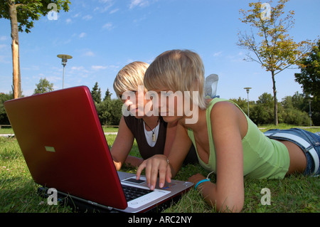 Junge Mädchen mit laptop auf wiese - giovani ragazze giacente in erba lavora con i notebook Foto Stock