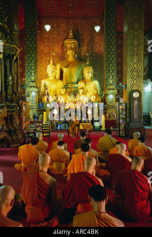 I monaci seduti all'interno del tempio Wat Phra That Hariphunchai, Lamphun, Thailandia del Nord Asia Foto Stock