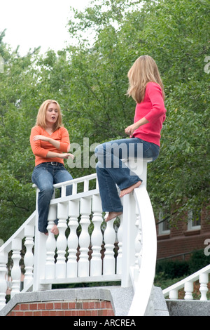 Due sorelle seduti sulla cima di una recinzione Foto Stock