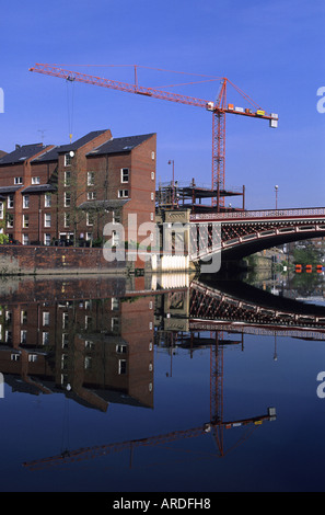 Gru sul sito di costruzione si riflette nel fiume aire che scorre attraverso la città di Leeds REGNO UNITO Foto Stock