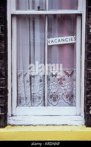 Close up di stretta finestra a ghigliottina con sfald vernice e sudicio cotto contenente tendina e un segno di sbieco Posti vacanti Foto Stock