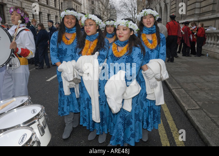 Giovani cheerleaders per hawaiano High School band in abiti blu con fiore stringitesta e lei tenere camici per London street Foto Stock