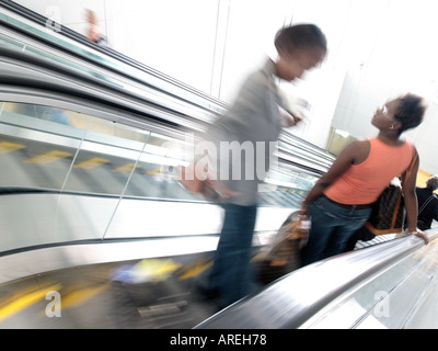 Aeroporto patroni cavalcare le scale mobili tra il terminale cancelli e trasporto a terra all'Aeroporto Internazionale di Dulles Foto Stock