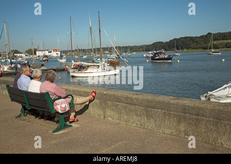 La gente seduta su una panchina guardando oltre il Fiume Deben, Woodbridge, Suffolk, Inghilterra Foto Stock