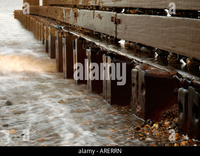 Acciaio e legno groyne happisburgh sulla spiaggia con acqua di mare e le onde sulla ghiaia, norfolk England Regno Unito Foto Stock