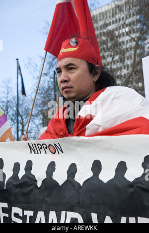 L uomo indossa rosso aveva birmano e porta e indossa bandiera dietro banner all inizio della Birmania la pace cammina, Londra, 5 gennaio, 2008 Foto Stock