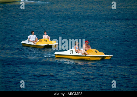 Le famiglie possono usufruire del divertimento di spingere i loro giallo e bianco numerati pedalo attraverso le calme acque della baia di Porto Rico Foto Stock