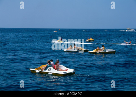 Le famiglie possono usufruire del divertimento di spingere i loro giallo e bianco numerati pedalo attraverso le calme acque della baia di Porto Rico Foto Stock