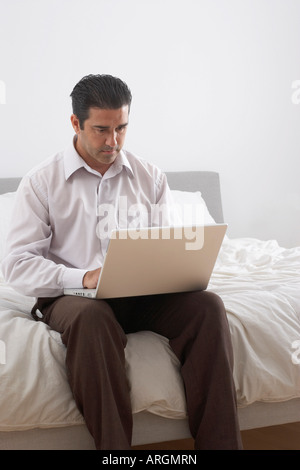 Uomo con notebook sul letto Foto Stock