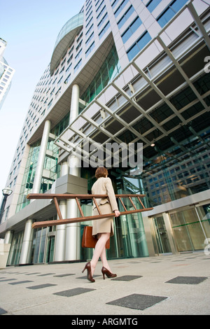 Imprenditrice entrando edificio, tenendo la scala Foto Stock