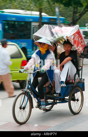 In rickshaw Driver donna musulmana con passeggeri di Sanya Hainan Island in Cina Settembre 2007 Foto Stock