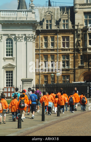 Università di Cambridge città parte di giovani turisti vestiti di colore arancio brillante mac di plastica molto calde estati asciutte giorno su re Parade Foto Stock