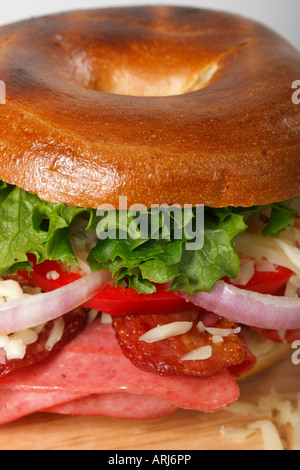 Prepara un panino ripieno al bagel con verdure gustose e prosciutto, un'insalata su un tavolo dalla parte anteriore sopra la verticale nessuno negli USA ad alta risoluzione Foto Stock