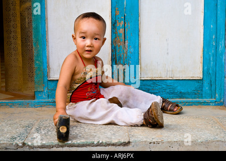 Giovani asiatici orientali cinese contadina ragazzo con un martello in mano seduta Cina JMH3031 Foto Stock