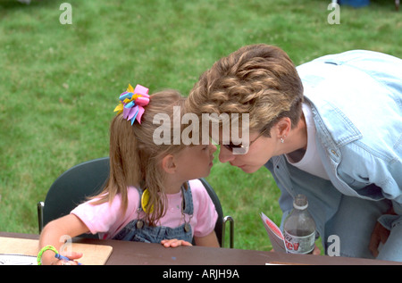 Ragazza whispering in madri di età ad orecchio 30 e 3. Fiume Mississippi Carp Festival Brooklyn Park Minnesota MN USA Foto Stock