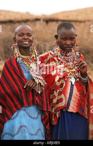 Le donne Masai che nel loro villaggio che mostra i loro costumi colorati, collane ed orecchini e guardando la telecamera. Foto Stock