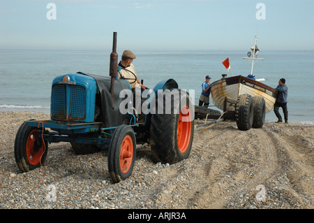 Regno Unito, Norfolk, Cromer, tre pescatori con il trattore tira barca sulla spiaggia Foto Stock