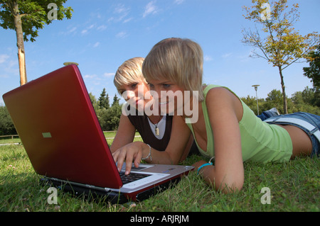 Junge Mädchen mit laptop giovani auf wiese - ragazze giacente in erba lavora con i notebook Foto Stock