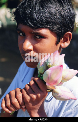 Ritratto di un ragazzo holding boccioli di loto dal lago a Kurunegala, centro dello Sri Lanka Foto Stock