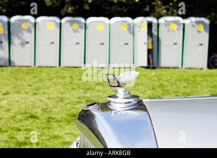 Argento auto Bentley parcheggiato di fronte alla fila di bagni portatili Foto Stock