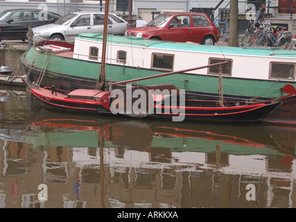 Una tradizionale piccola barca a vela con schede di lee ormeggiato a fianco di una chiatta Amsterdam Olanda 24 Aprile 2006 Foto Stock