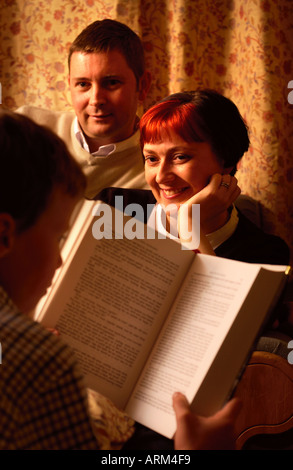 Una madre e un padre ascoltando il loro bambino la lettura a voce alta Foto Stock