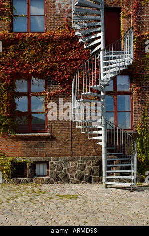 Uscita di emergenza al ivyed muro di mattoni Foto Stock