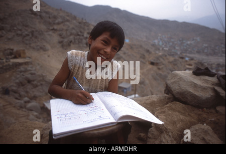 Ragazzo scuola studiare a casa sua in una baraccopoli sul versante di una montagna sulla periferia di Lima, Perù Foto Stock