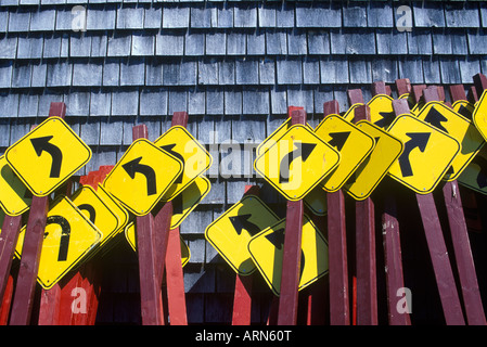 La curva più avanti cartelli affastellati assieme contro cedro parete incastrata, British Columbia, Canada. Foto Stock