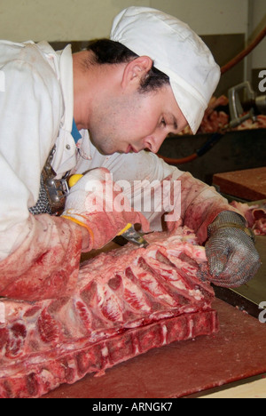 Carni bovine carve dissezionare joint rosa rosso sangue gore di lavoro tavolo di lavoro osso coltello fetta tagliata dissezionare separare tagliare la pelle del mattatoio di osso di pelle Foto Stock