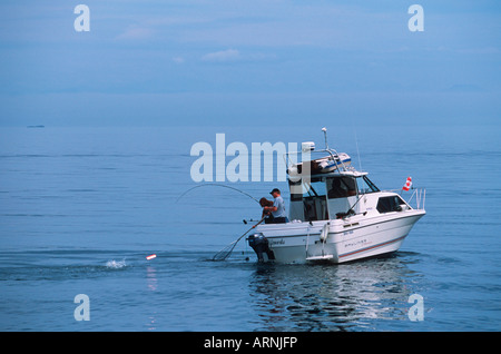 Due uomini la riproduzione di salmone su piccole barche da pesca, Isola di Vancouver, British Columbia, Canada. Foto Stock