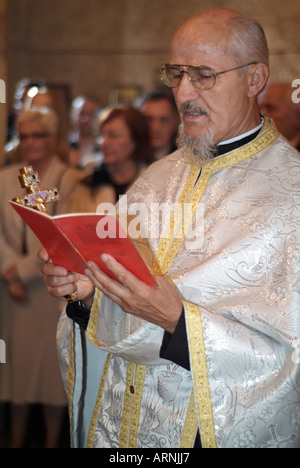 Sacerdote ortodosso tenendo una lettura come parte di una cerimonia di matrimonio Foto Stock