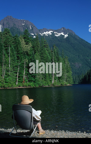 Schoen lago con la donna più anziana lettura sul litorale, Isola di Vancouver, British Columbia, Canada. Foto Stock