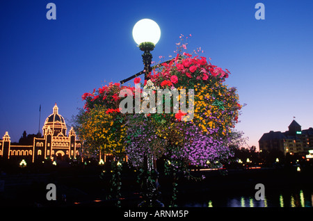 Al crepuscolo con fiori sul cavalletto di luce e legislatore illuminato, Victoria, Isola di Vancouver, British Columbia, Canada. Foto Stock