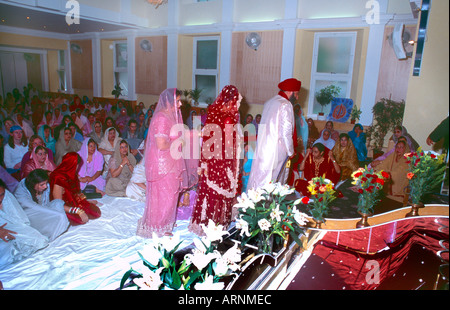 La religione sikh matrimonio sposa e lo Sposo Walking Round Guru Granth Gurdwara centrale Shepherds Bush London Inghilterra England Foto Stock