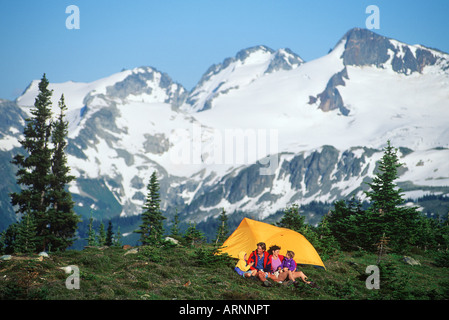 Coppia giovane nei campi a prato con sfondo di montagne di Whistler Alpine di Whistler, British Columbia, Canada. Foto Stock