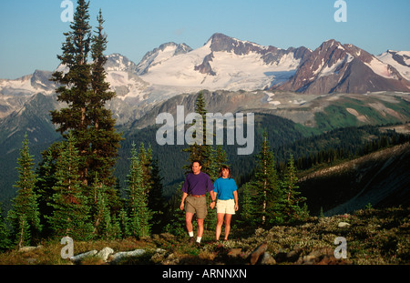 Coppia giovane passeggiate nel prato alpino sulla cima di Whistler, British Columbia, Canada. Foto Stock