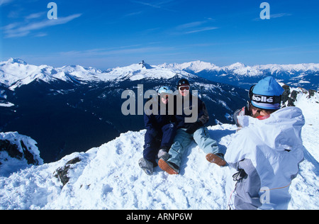 Gli appassionati di snowboard sulla sommità di picco prendere foto con Garibaldi montagna nera e il brosmio oltre, Whistler, British Columbia, Canada. Foto Stock