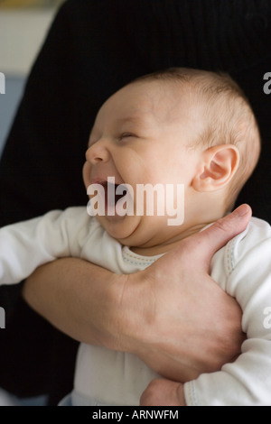 Di due mesi di età bambino ridere in madre di braccia Foto Stock