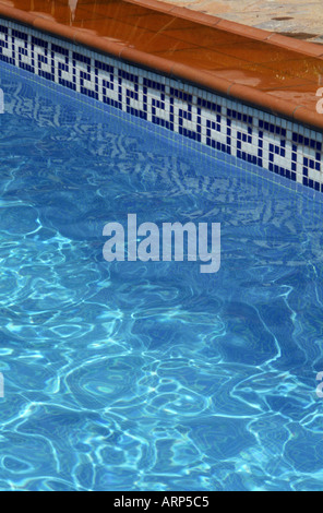 Astratto della piscina con il sole che gioca sulla superficie di acqua blu e mosaico tegole modello intorno bordo. La Manga, Murcia, Spagna. Foto Stock