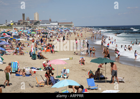 Lungo la surfline di jersey shore spiaggia con gente che cammina, permanente e spruzzi in fondali bassi. Foto Stock