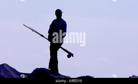 Il pescatore tenendo la canna da pesca stagliano contro un mauve cielo mattutino. Foto da Jim Holden. Foto Stock