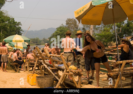 I turisti a bere al Riverside swing bar mentre il tubo verso il basso il Nam Xong fiume Vang Vieng Laos Foto Stock