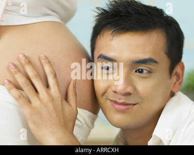 L'uomo ascoltare a donne in stato di gravidanza womans stomaco Foto Stock