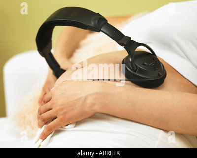 Close up della donna incinta con le cuffie Foto Stock
