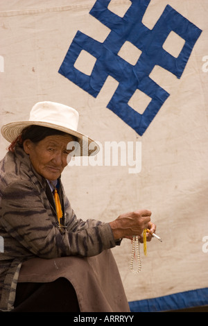 Donna di fronte a 'nodo di eternità' vicino il tempio del Jokhang, Lhasa, in Tibet. Foto Stock