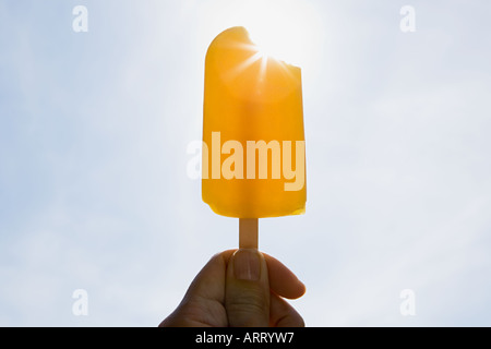 Persona in possesso di un per lecca-lecca di ghiaccio in una giornata di sole Foto Stock