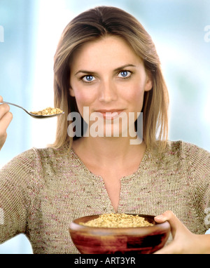 Una donna con una ciotola e cucchiaio di farina di avena Foto Stock